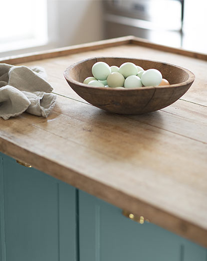 a wooden bowl holding about three dozen eggs